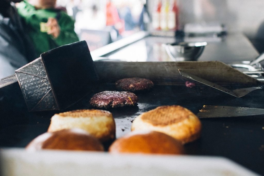 Grillplatte im Einsatz in einem Foodtruck: Burger-Patties und Brötchen beim Garen